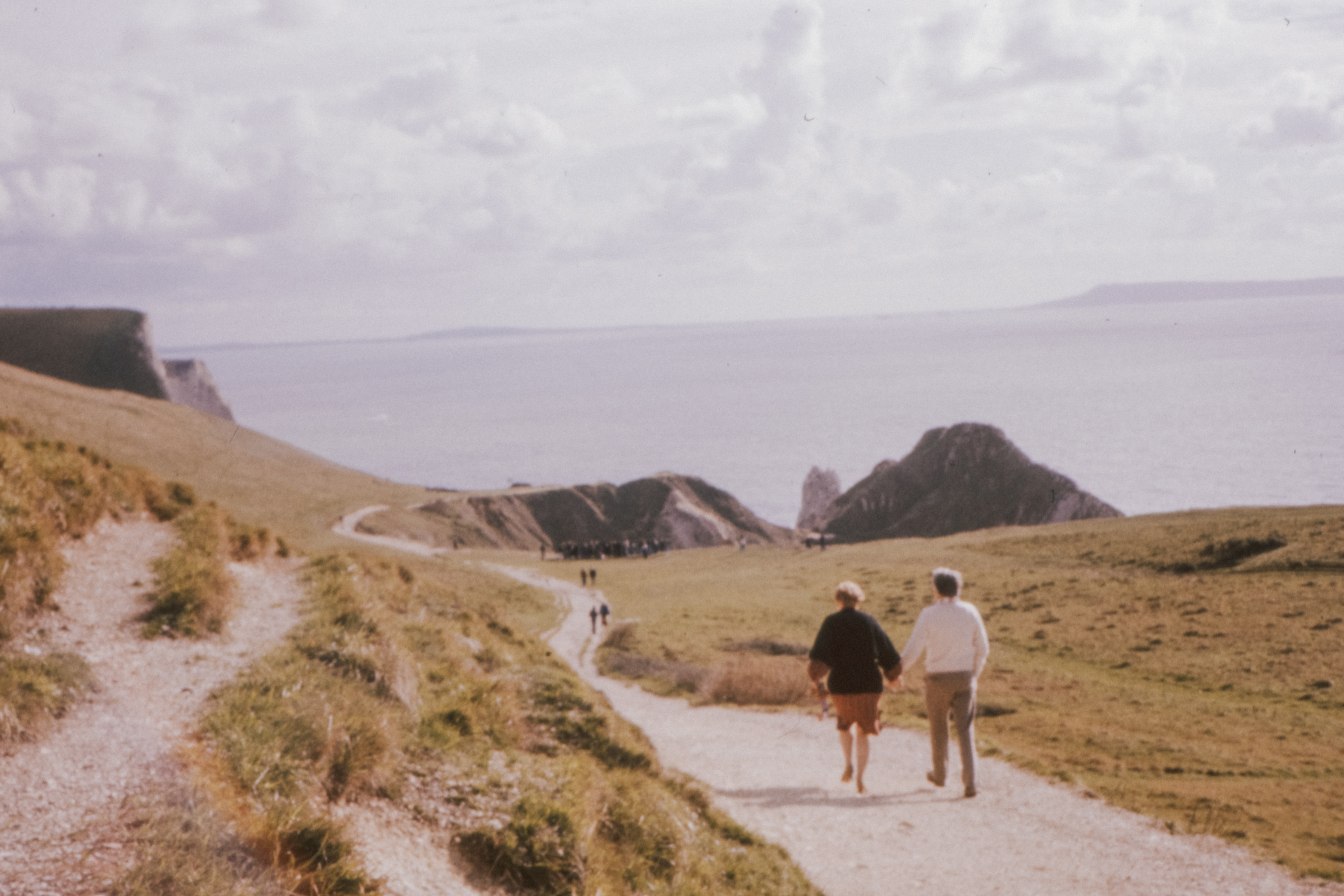 romantic elderly couple walking on durdle door's hill